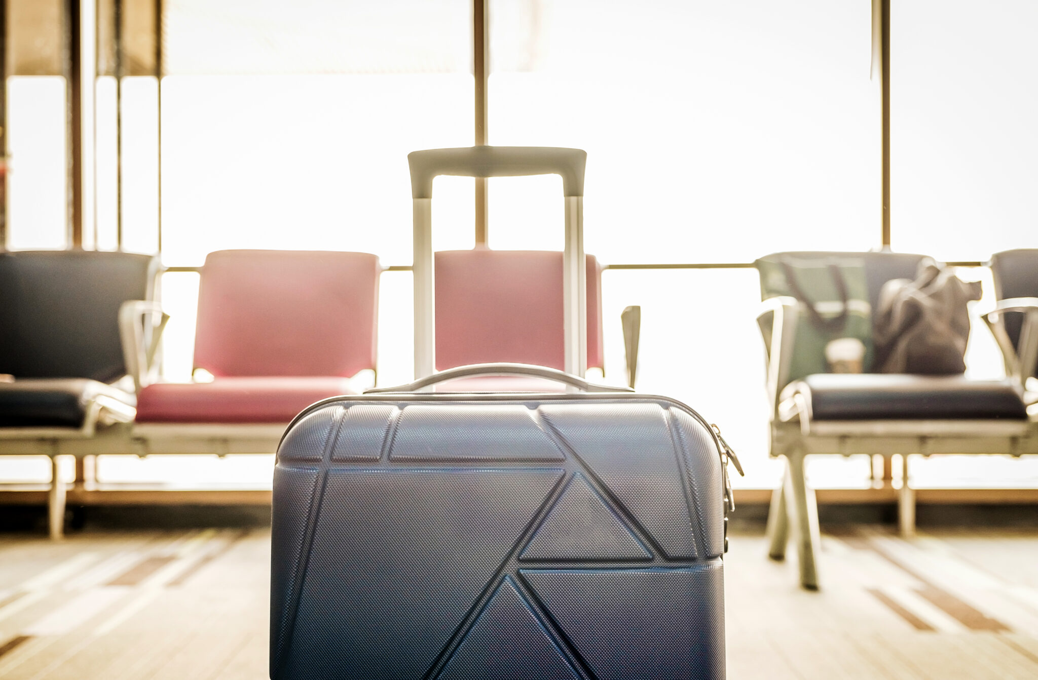Close up Suitcases in airport departure terminal with terminal waiting seat at background,Holiday vacation concept, Business trip,selective focus on suitcases,vintage filter.